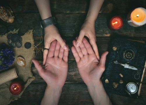 Palmistry concept. Fortune teller reading future on the hand on a magic table background. Future reading concept.